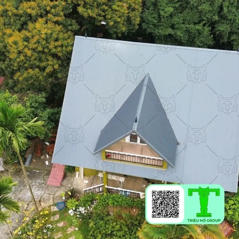 Ngôi nhà mái tôn màu xám nhìn từ trên cao giữa cây xanh