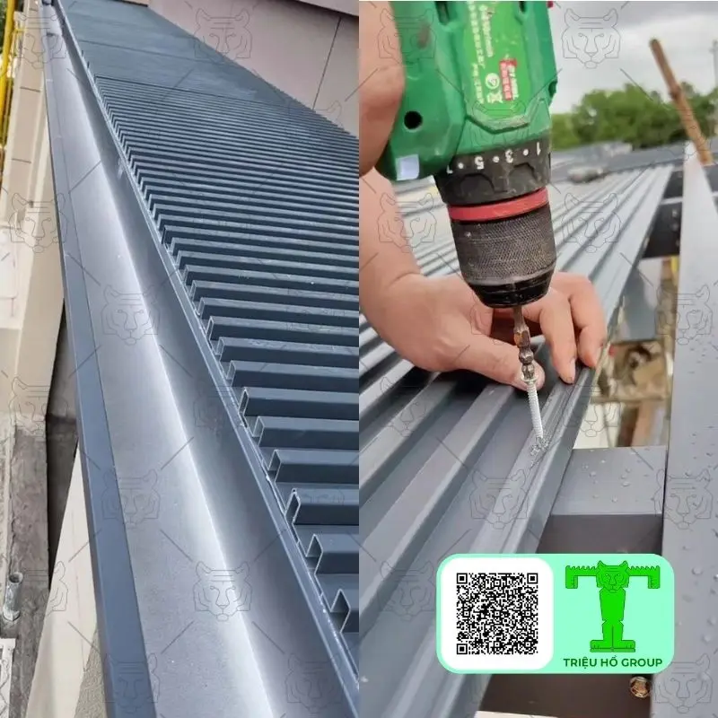 Người thợ dùng máy khoan bắt vít tấm lợp kim loại màu xám lên khung mái, bên cạnh là máng xối thoát nước