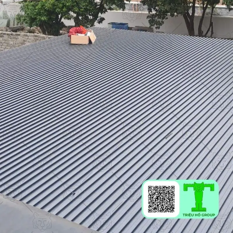 Mái tấm lợp hợp kim nhôm màu xám với các đường sóng đều đặn và một hộp carton trên đó