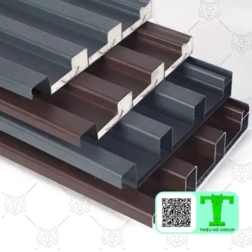 Các tấm lợp hoặc phụ kiện mái nhôm có biên dạng sóng, màu xám đậm và nâu, được xếp chồng lên nhau, một số hiển thị mặt cắt